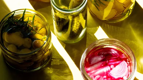 Glass jars with pickled vegetables, in sunlight.