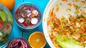 Pickled vegetables and citrus on blue table.