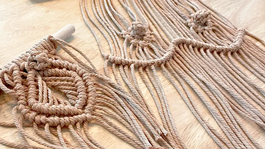 Macrame wall hanging on wooden table.