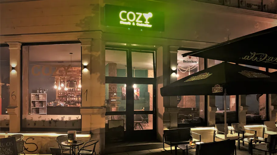 Gemütliche Restaurantfassade bei Nacht, Straßensitzplätze.