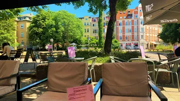 Outdoor cafe with seating and vibrant buildings.
