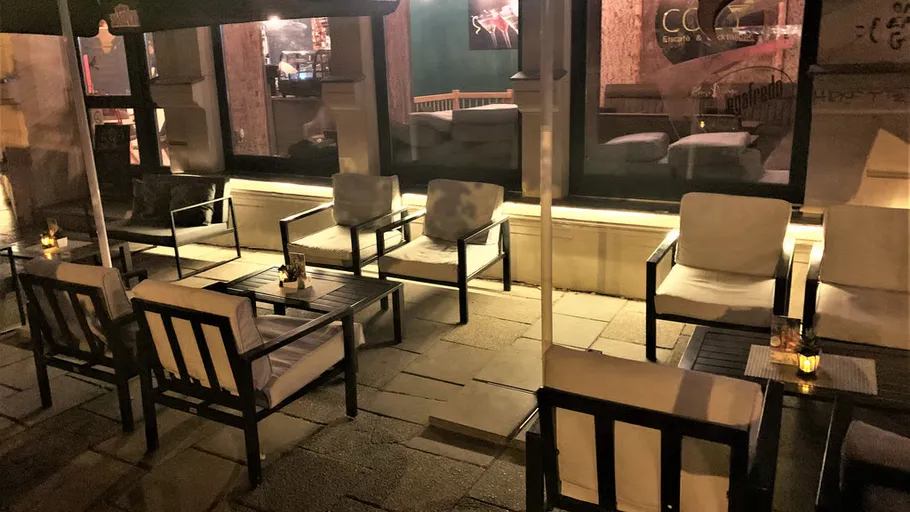 Terrasse mit Stühlen und Tischen bei Nacht.