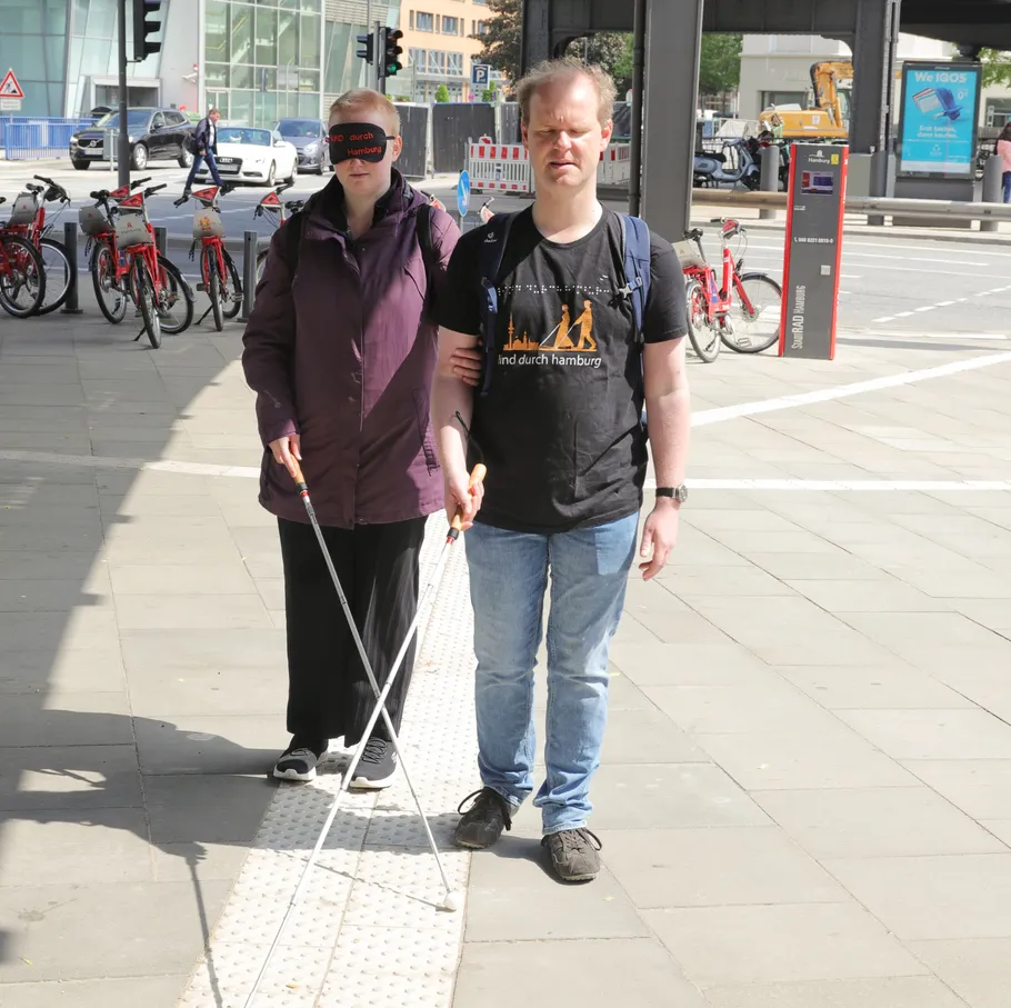 Two people with canes walking together outside.