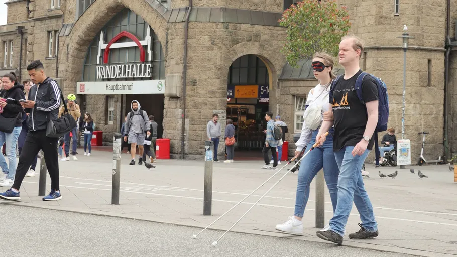 Two people with canes walking near train station.