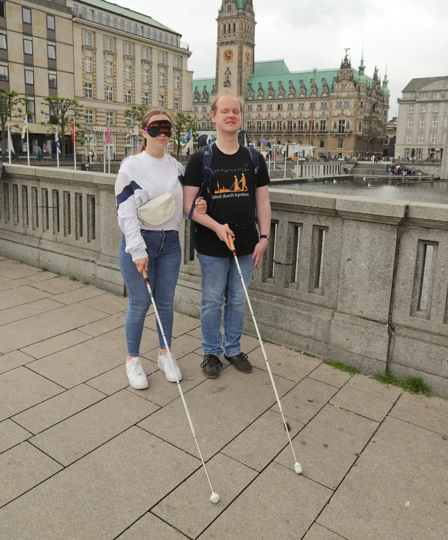 Two people with canes standing on city bridge.