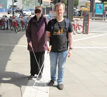 Zwei blinde Personen gehen auf Stadtstraße.