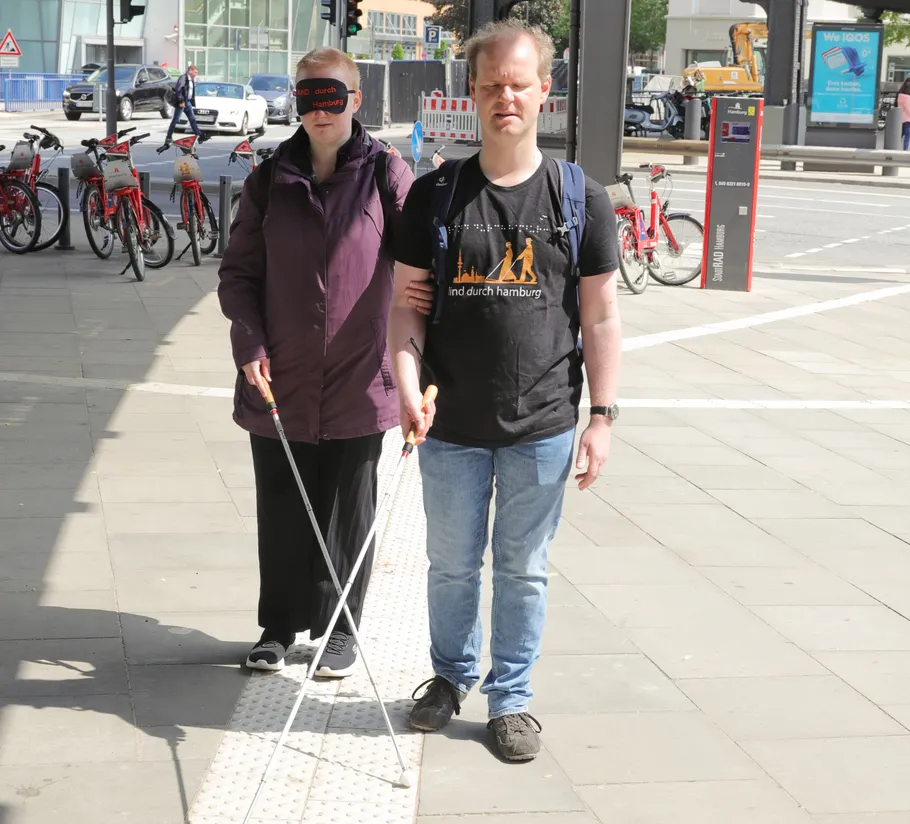 Two blind people walking on city street.