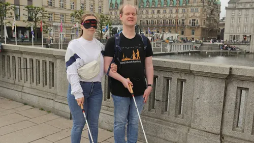 Two people with canes walking on bridge.
