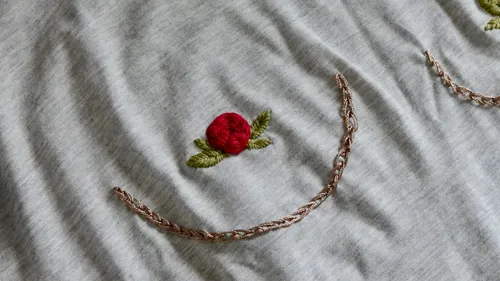 Red rose embroidery on gray fabric.