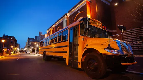 Yellow school bus parked on city street at night.