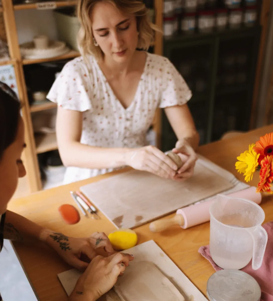 Two women crafting clay at a table.