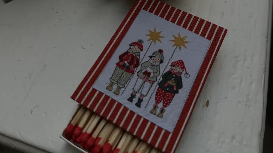 Festliche Streichholzschachtel mit drei illustrierten Kindern.