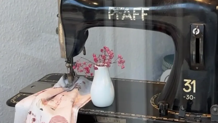 Sewing machine with fabric and vase inside.