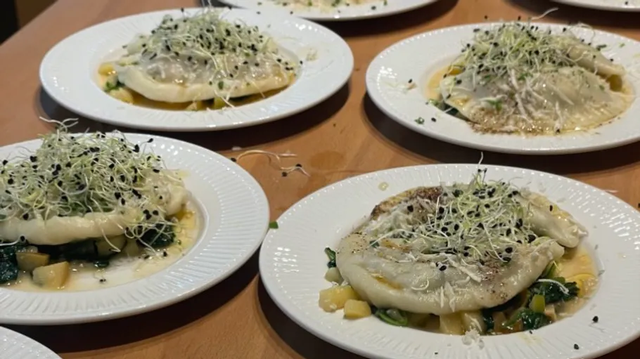 Plates of stuffed pasta topped with sprouts.