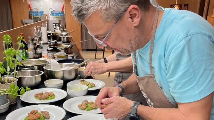 Koch richtet Essen in einer Küche an.