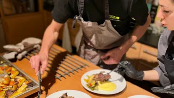 Chefs plating food in kitchen setting.