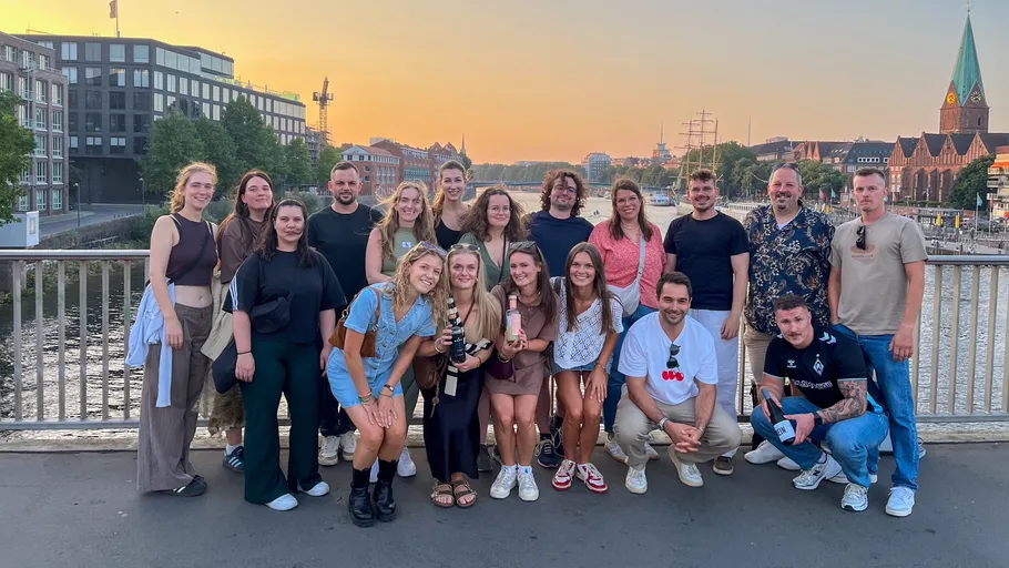 Gruppe von Menschen posiert auf einer Brücke bei Sonnenuntergang.
