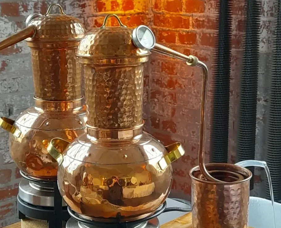 Kupferdestillen auf Tisch, Ziegelwand Hintergrund.