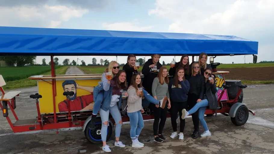 Gruppe von Menschen posiert mit Bierbike im Freien.