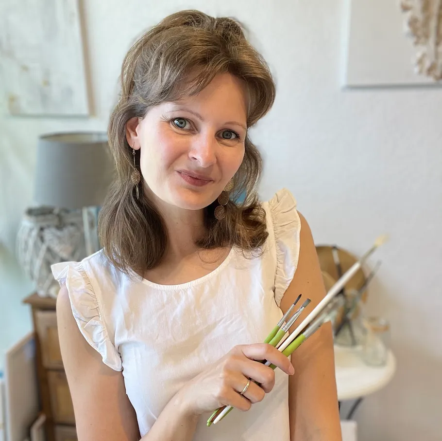 Woman holding paintbrushes in art studio.