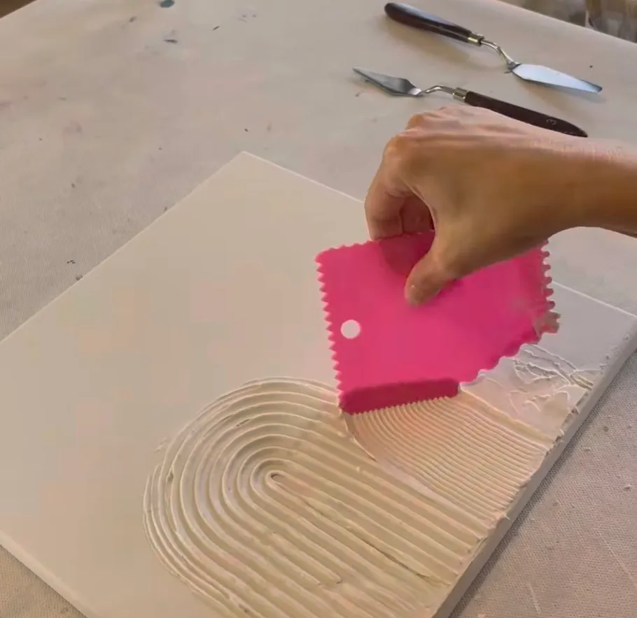 Hand spreading texture paste on canvas.