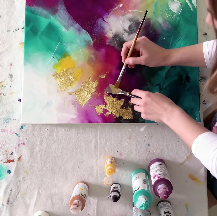 Person painting abstract art with gold foil.