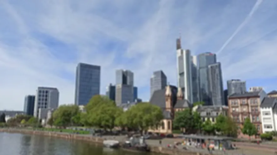Skyscrapers along river with trees and buildings.