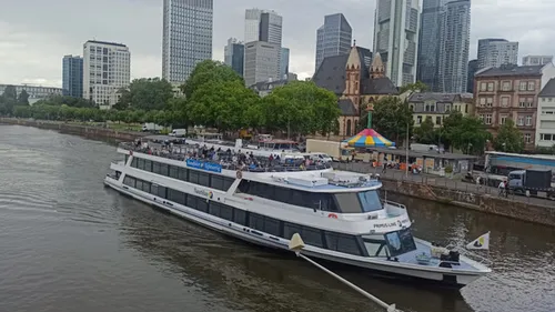 Boat sailing on river by city buildings.