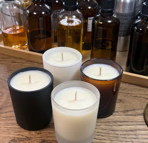 Four candles on a wooden table with bottles.