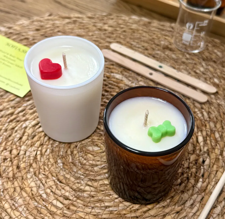 Candles with heart and bone shapes on woven mat.