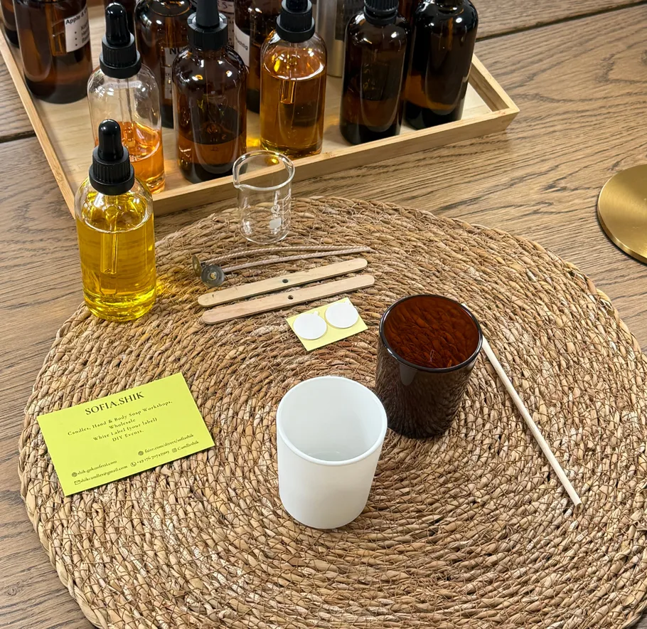 Kerzenherstellungswerkzeuge auf geflochtenem Untersetzer, Holztisch.