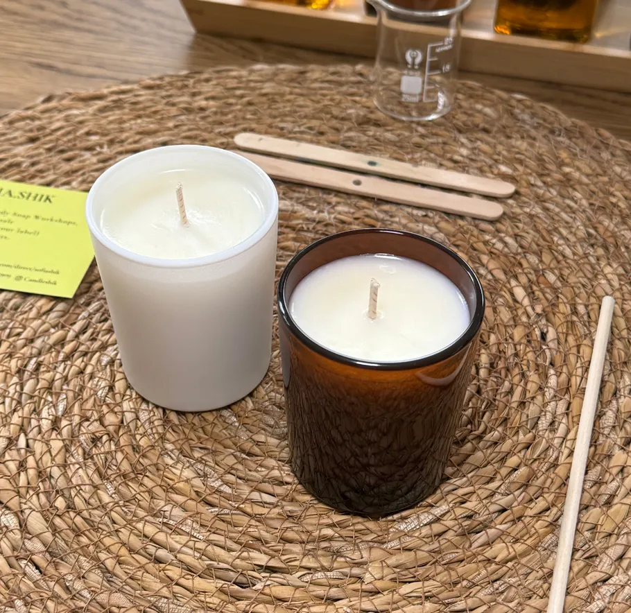 Two candles on woven placemat with utensils nearby.