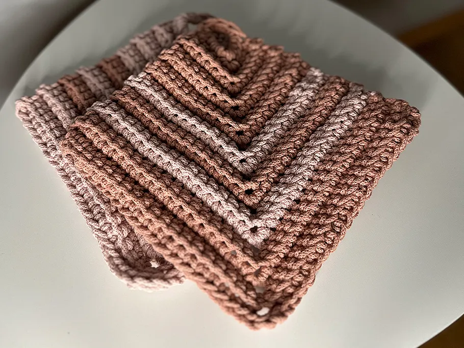 Crocheted brown dishcloths folded on table.