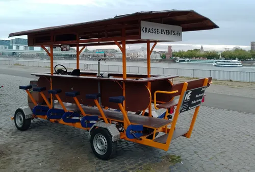 Pedal bar cart parked by river, empty seats.