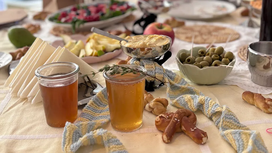Person knitting at a dining table with food.