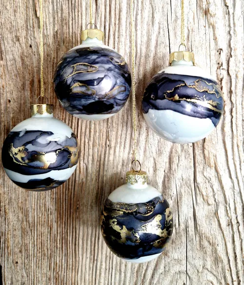 Four marbled ornaments hanging on wood background.