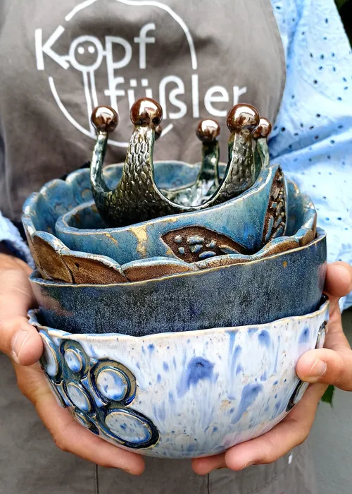 Person holds artistic blue handmade bowls.