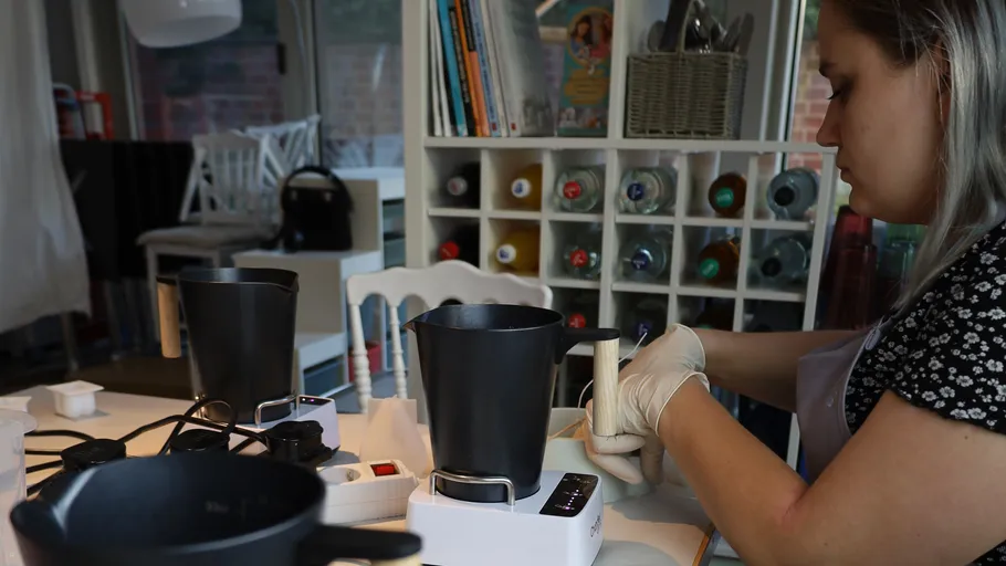 Woman making candles in craft room.