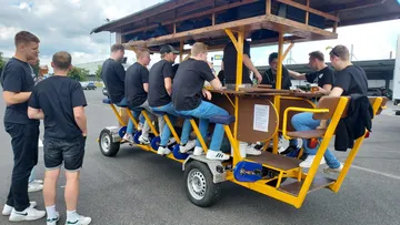 Group drinking on a pedal-powered bar outdoors.