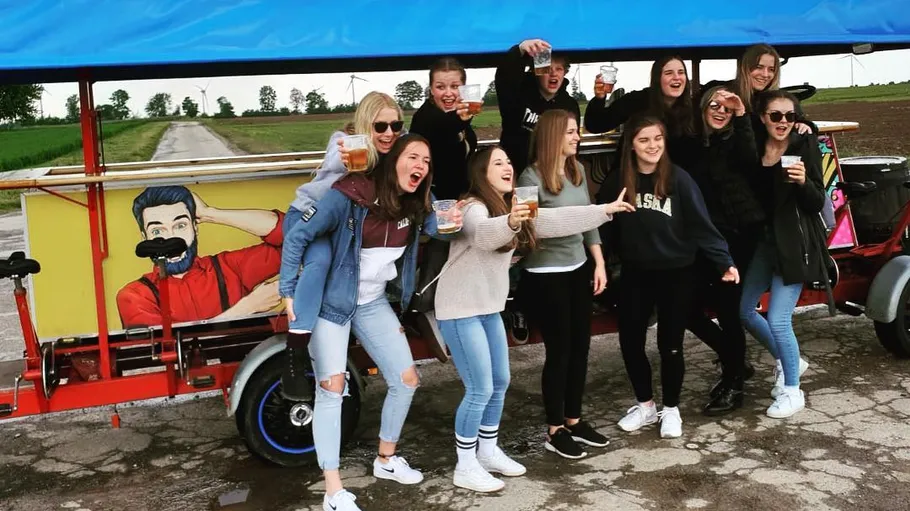 Gruppe von Menschen feiert auf Partybike draußen.