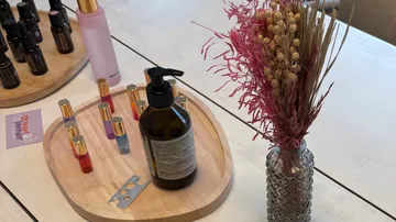 Essential oils and dried flowers on wooden table.