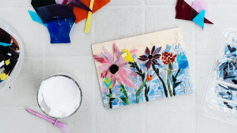 Mosaikblumen auf Fliese mit Glasstücken.