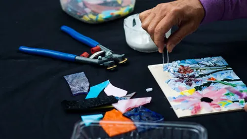 Hand arranging mosaic pieces on a table.