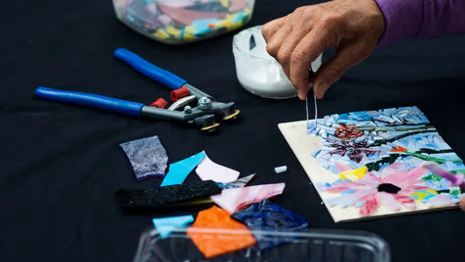 Hand arranging mosaic pieces on a table.