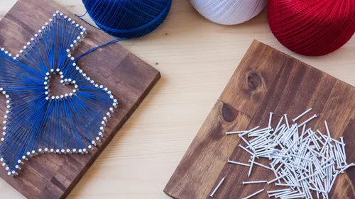 String art with yarn and nails on wood.