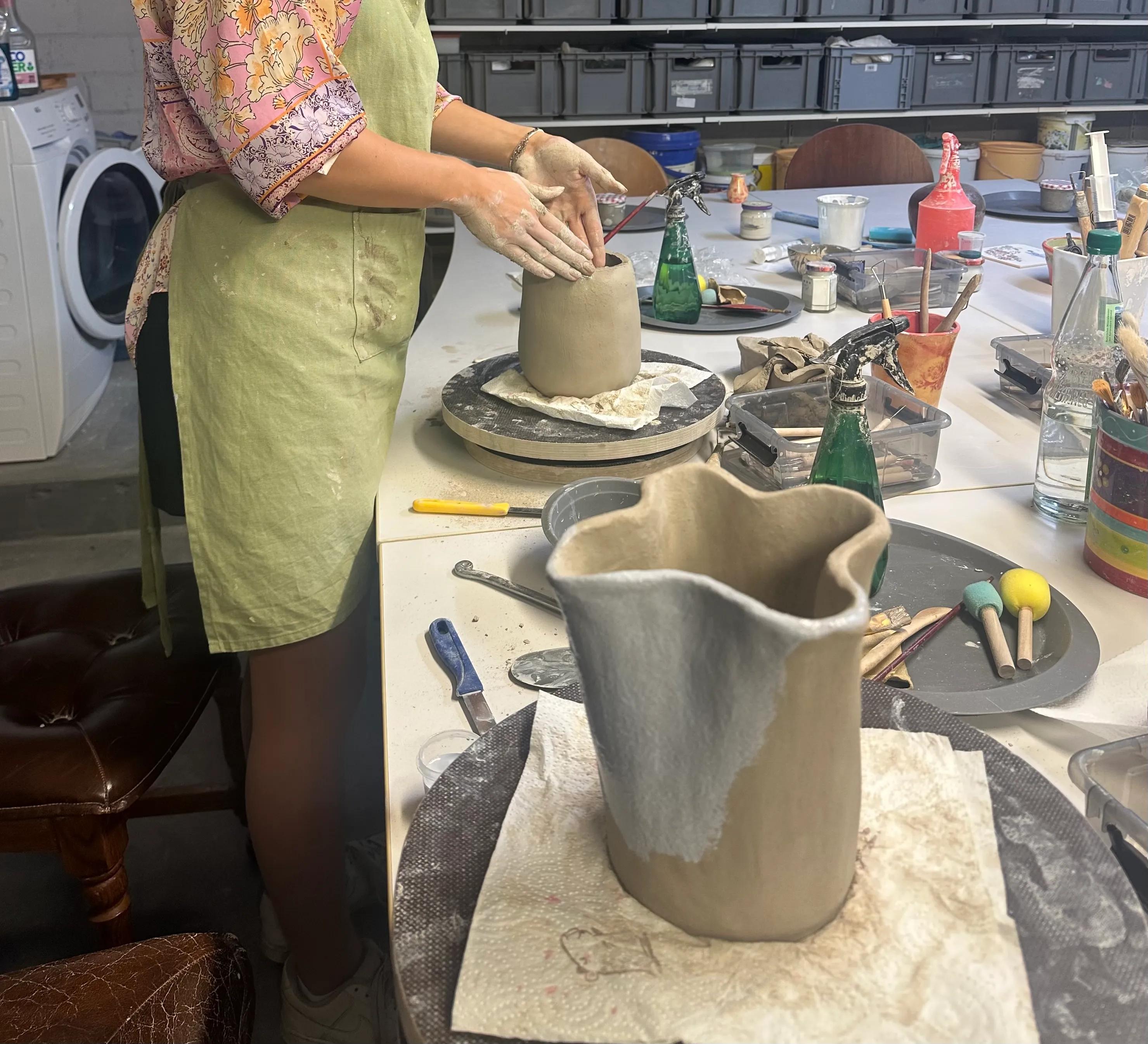 Person shaping clay vase in pottery studio.