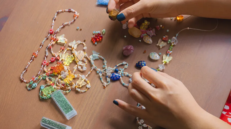 Hands crafting necklaces with colorful beads.