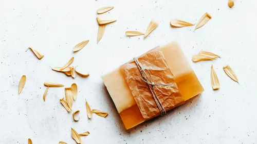 Soap bar wrapped with petals on table.