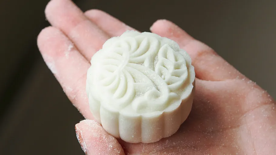 Small white mooncake held in hand.