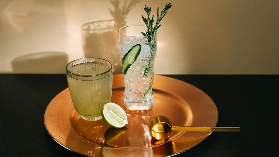 Zwei Getränke mit Limette und Rosmarin auf Tablett.